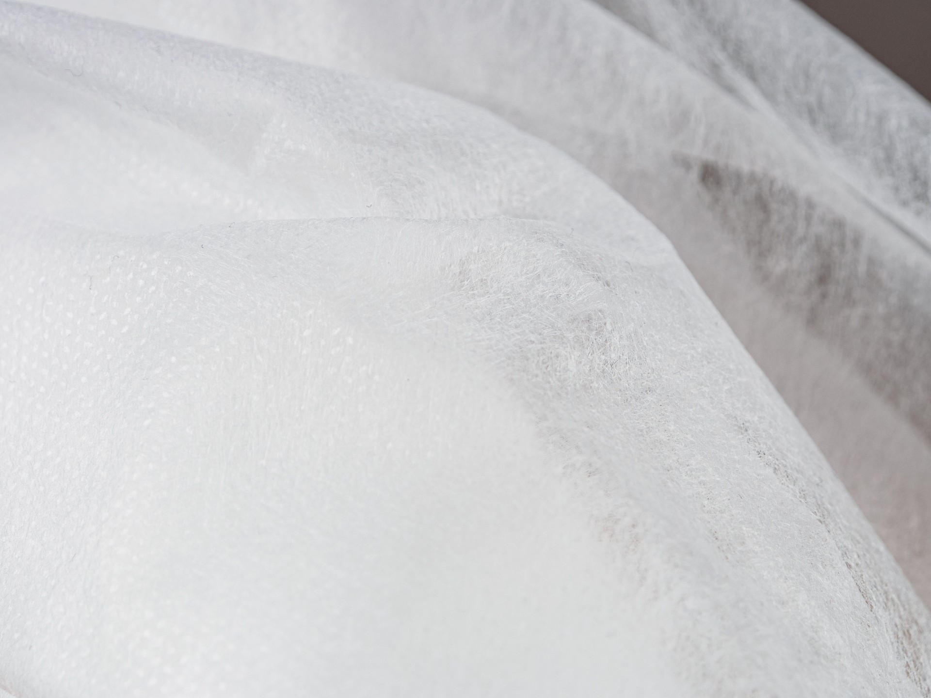 Lightweight, flexible nonwoven fabric. Ideal for various applications. Material properties & textile construction visible.